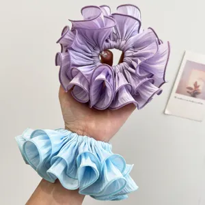 Detailansicht großer gerüschter Scrunchies in Lila und Blau in der Hand