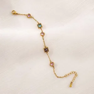 Vista dettagliata di un bracciale dorato in acciaio con zirconi colorati a cuore e quadri