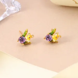 Detail view of floral stud earrings with purple rhinestones and yellow enamel flowers