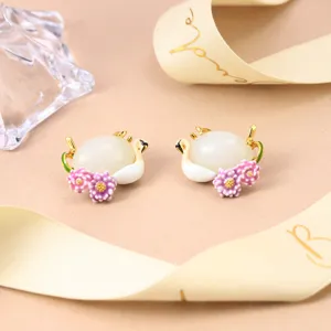 Close-up of elegant swan earrings with enamel flowers and white gemstone centers