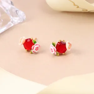 Detail view of retro floral stud earrings with red square gemstone and enamel flowers