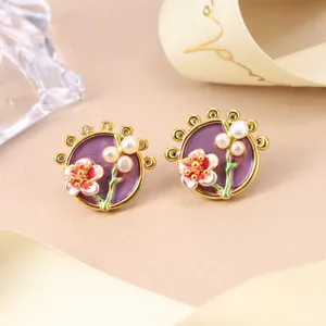 Detailed close-up of floral enamel earrings with pearls in a vintage style.