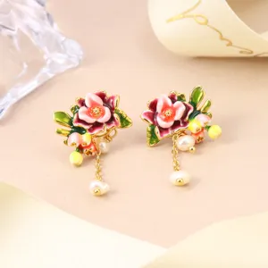Detailed macro view of floral enamel earrings with pearl tassels and gold accents.