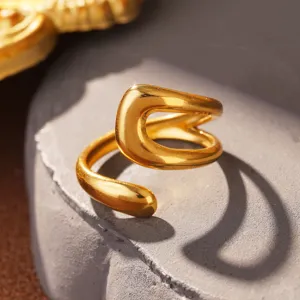 Makro-Detail eines goldfarbenen Titanstahlrings mit fließenden, organischen Linien.