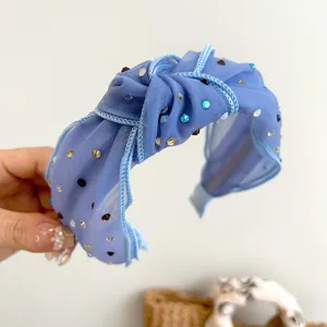 Detail van een blauwe geknoopte mesh-hoofdband met fonkelende gekleurde strass