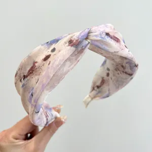 Detail of wide-brimmed cross headband with elegant purple watercolor pattern.