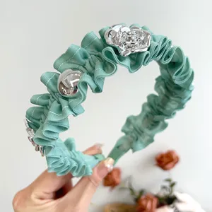 Nahaufnahme von minzgrünem Rüschen-Haarreif mit eleganter silberner Rose und Perlen.