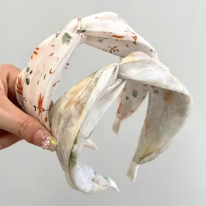 Close-up detail of two wide cross headbands featuring elegant floral and leaf patterns