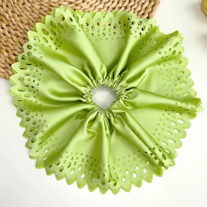 Vue détaillée d'un chouchou en satin vert surdimensionné à plis creux et bords découpés au laser.