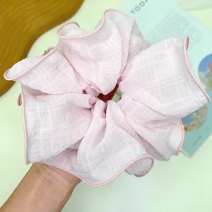 Primer plano de un scrunchie rosa de gran tamaño con textura de rejilla y volantes.