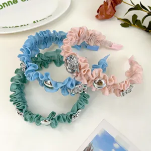 Detailansicht von pastellfarbenen Rüschen-Haarbändern mit metallischen Rosen-Akzenten