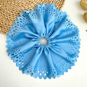 Vue détaillée d'un grand chouchou plissé bleu avec des motifs élégants découpés au laser
