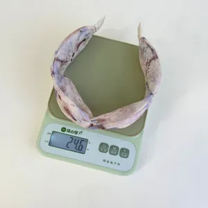 Detail shot of a new Chinese style floral cross headband showing weight of 24.6g on a scale