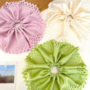 Détail de chouchous plissés ajourés surdimensionnés de couleurs rose, blanc et vert clair.