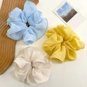 Detalle de tres elegantes coleteros con textura de rejilla y volantes en azul, amarillo y crema