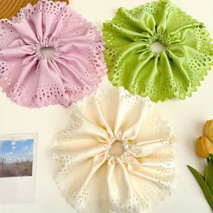 Détail macro de chouchous géants ajourés en rose pastel, vert et crème