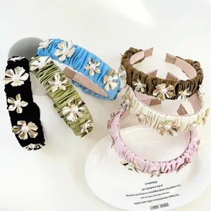 Close-up of elegant pleated headbands with metallic flowers and pearls