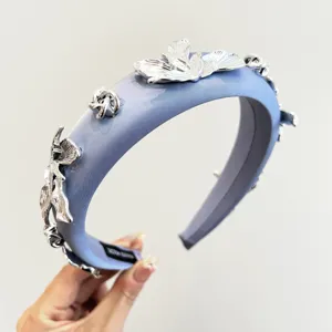 Gros plan d'un serre-tête en satin bleu orné de détails floraux en métal argenté.