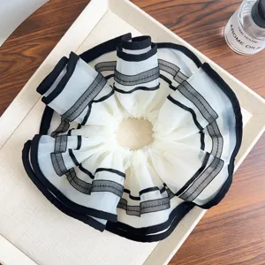 Detailansicht eines großen Netz-Scrunchies mit eleganten schwarzen Streifen