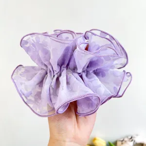 Macro view of a purple double-layered lace scrunchie showing delicate floral patterns
