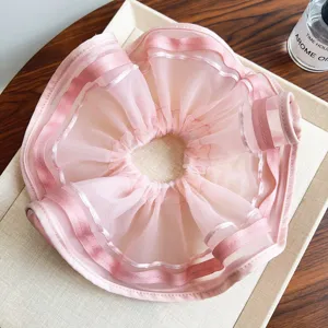 Makroaufnahme des rosa gefalteten Mesh-Haargummis mit eleganten Satinbandkanten