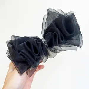 Vue détaillée d'un élégant nœud à cheveux en organza noir avec un centre en strass étincelant.