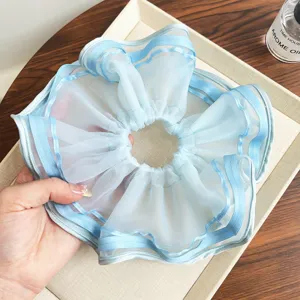 Nahaufnahme eines hellblauen Organza-Haargummis mit plissiertem Netz und Satinrand