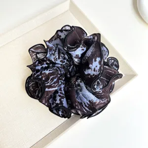 Detail view of tie-dye fabric scrunchie with ruffled layers and black piped edges