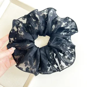 Close-up detail of a elegant black floral lace oversized scrunchie for hair styling