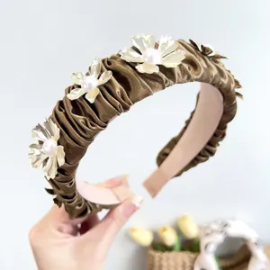 Detailed view of elegant bronze pleated headband featuring metal flowers and white pearls