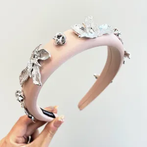 Vue détaillée des ornements floraux en métal argenté sur un serre-tête en satin rose