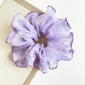 Close-up detail of a purple floral lace scrunchie featuring delicate ruffled edges for hair