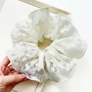Close-up of white double-layered lace floral scrunchie hair tie for bun hairstyles