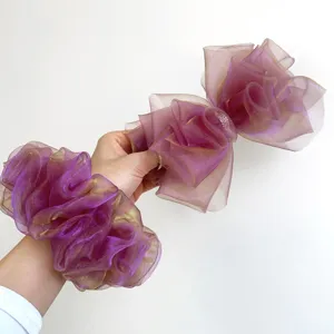 Détail d'un ensemble élégant chouchou et barrette à nœud en organza irisé violet pour femme.