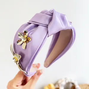 Vue détaillée d'un serre-tête en satin violet orné de fleurs décoratives en métal doré