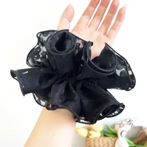 Close-up view of a stylish black double-layer lace scrunchie worn on the wrist for scale