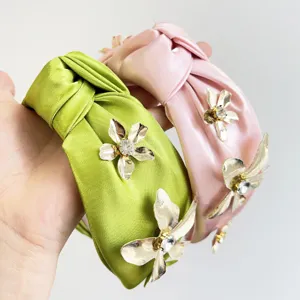 Détail rapproché de bandeaux en satin noués avec fleurs en métal et cœurs en cristal.