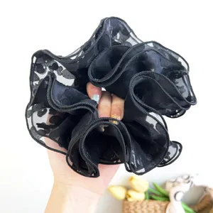 Detailed view of a black floral lace oversized scrunchie showing delicate mesh texture