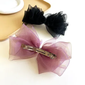 Détail d'un grand nœud à cheveux en organza montrant le clip métallique à l'arrière