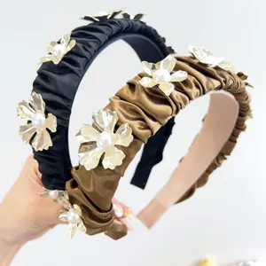 Close-up detail of ruched satin headbands decorated with metal flowers and white pearls