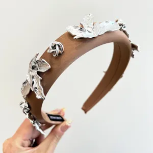 Détail d'un serre-tête rembourré marron avec des fleurs métalliques argentées décoratives