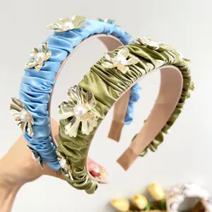 Detail of elegant ruffled headbands with gold metal flowers and pearls decoration.