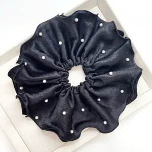 Vista detallada de un coletero de satén negro de estilo francés con elegantes perlas blancas.