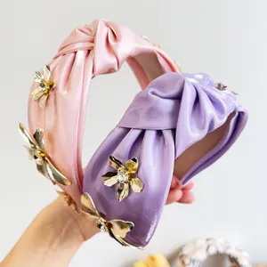 Détail rapproché de serre-têtes en satin noué avec d'élégantes fleurs en métal et strass