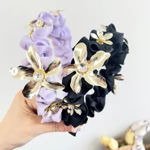 Detalle de diademas de satén fruncido con flores de metal dorado y brillantes