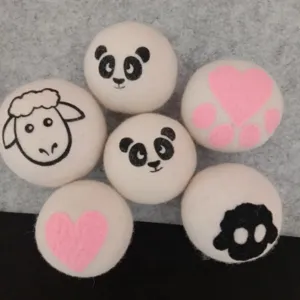Primo piano di palline per asciugatrice in lana bianca con motivi di panda e cuori