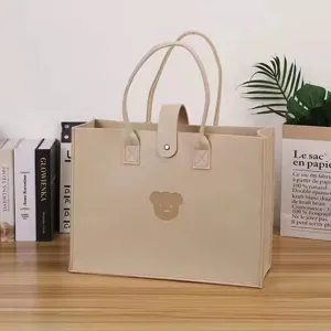Close-up of a beige felt tote bag featuring a cute bear patch in a cozy lifestyle setting