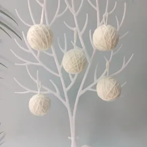 Palline di lana bianca da 5 cm appese a un albero per decorazioni natalizie fai da te.