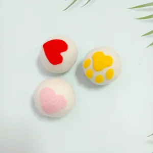 Dettaglio di palline per asciugatrice in lana con motivi a cuore e zampa.