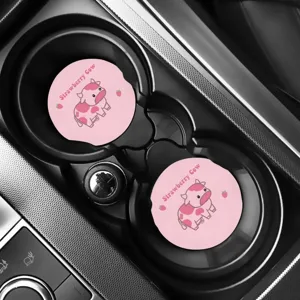 Detailansicht der rosa Erdbeerkuh-Filzuntersetzer im Getränkehalter eines Autos.